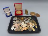 un plateau rempli de pièces de monnaie et une médaille posés sur une table