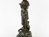 a bronze statue of a woman holding a dog on a rock
