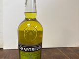une photo d'une bouteille de Chartreuse posée sur une table en bois