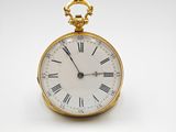 a close up of a gold pocket watch with roman numerals