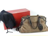 un sac à main marron et une boîte rouge posés sur une surface blanche