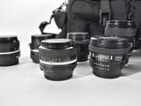 a lot of camera lenses and a bag on the table