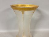 vase en verre jaune et blanc, bordé d'or, posé sur une surface blanche