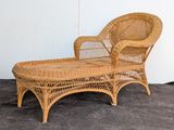 a wicker chaise sitting on the floor in front of a wall