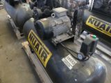 several air compressors are lined up on pallets in a warehouse