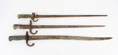 three old iron swords are displayed on a white surface