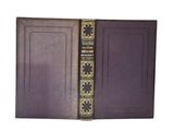 un vieux livre à la couverture violette et aux bordures dorées