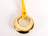 a gold coin hanging from a rope on a white surface