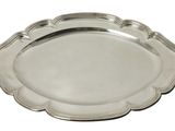 une assiette en argent aux bords festonnés sur fond blanc