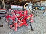une machine rouge qui est à l'arrêt dans la poussière