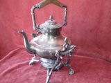 silver plated teapot on stand on red velvet background