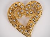 a close up of a heart shaped brooch on a white surface
