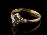 a close up of a gold ring with a diamond and blue sapphire