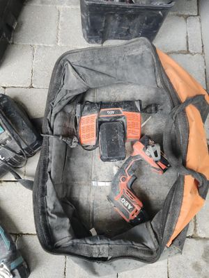 un sac contenant des outils posé par terre à côté de lui