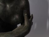 a bronze statue of a woman sitting on her knees