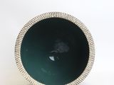 a green bowl with a silver rim on a white surface