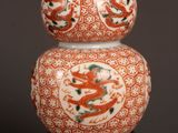 an orange and white vase sitting on top of a wooden stand