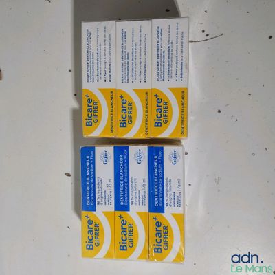 deux tubes de dentifrice posés sur une table blanche