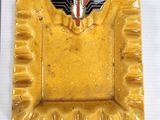 a yellow square plate with a winged emblem on it