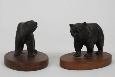 pair of black bear figurines on wooden bases on a white background