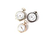 trois types de montres de poche sur une surface blanche