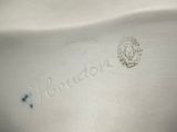 a close up of a white vase with a blue flower on it