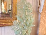 a vase with a plant on a table in front of a mirror