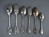 six silver spoons and a fork are lined up on a table