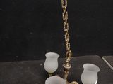 un lustre ancien en laiton avec des abat-jours en verre dépoli