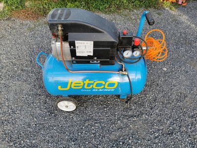 a small blue air compressor sitting on the gravel
