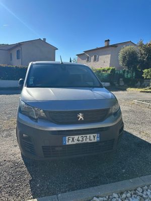 une voiture grise garée sur un parking à côté d'une maison