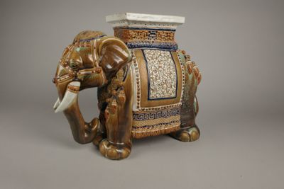 un éléphant en céramique avec un siège sur le dos