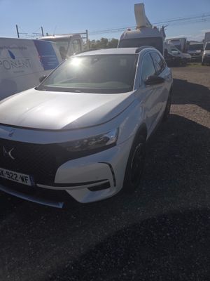 the front of a white car parked in a lot next to a trailer