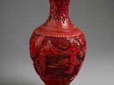 a red vase sitting on a table with a gray background