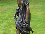 une statue représentant une femme tenant un sac à main dans un champ