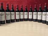 six bottles of red wine lined up on a wooden table