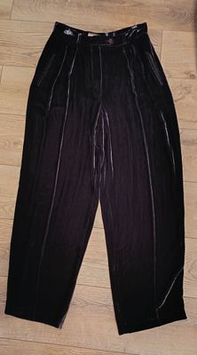 Le pantalon est noir et possède une fermeture éclair à la taille.
