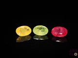 trois gemmes de couleurs différentes alignées sur une surface noire