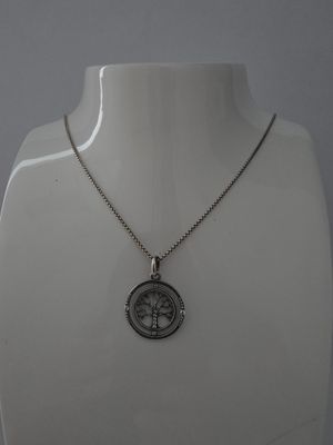 un torse de mannequin blanc portant un collier en argent orné d'un arbre de vie