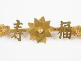 une image montrant un gros plan d'une broche en or sur fond blanc