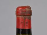a bottle of wine with a red cap on it