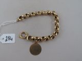 bracelet plaqué or avec une breloque en forme de pièce de monnaie et une étiquette de prix