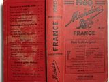 an old book with a red cover sitting on top of a table