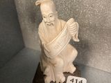a small statue of a man sitting on a wooden stand