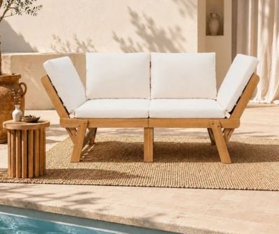 une photo d'un canapé blanc posé sur un tapis, près d'une piscine