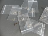 plusieurs morceaux de sacs en plastique transparent posés sur une table, à côté d'une paire de ciseaux