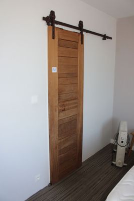 un lit blanc dans une chambre, à côté d'une porte en bois