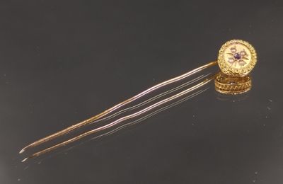 une épingle à cheveux dorée ornée d'une fleur violette