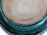 a close up of a green and white vase with a brown lid