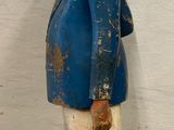 a wooden statue of a man with a blue jacket and white pants